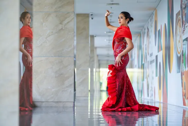 Elegant woman in artistic red gown posing in a modern indoor corridor. Celebrity color seasons: what to know and why