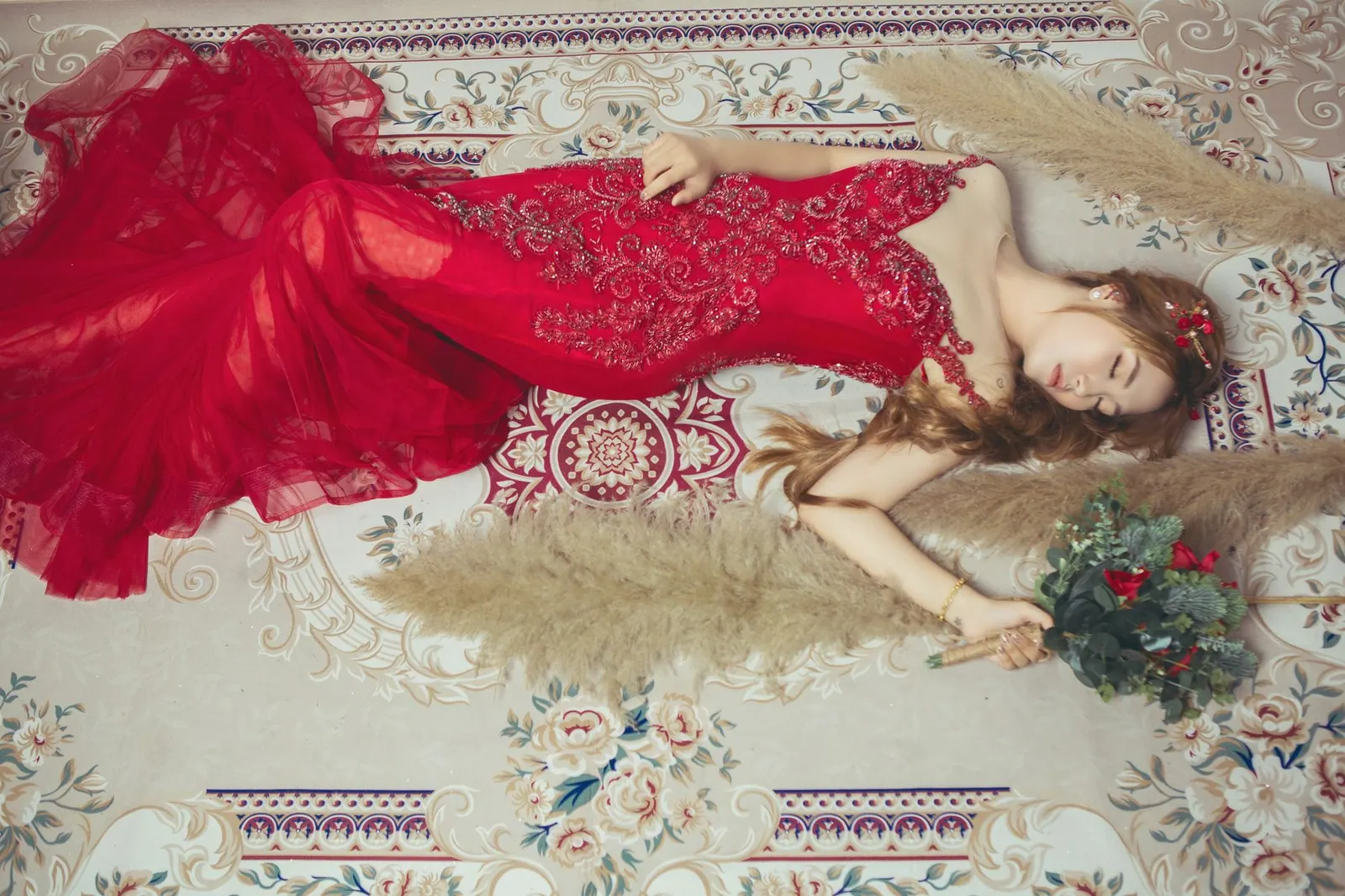 A fashionable woman in a red lace dress elegantly lies on a floral carpet, holding a bouquet. Cross-Border Dress Shopping: CAD Duties and Brokerage to Check