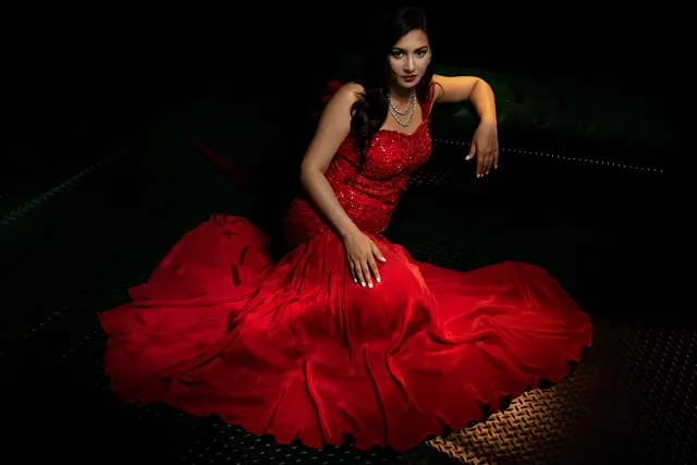 Captivating portrait of a woman in a red gown, exuding elegance and luxury against a dark backdrop. Jewelry and watch buying starts with a guide to checking construction